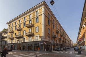 A multi-story building with balconies, storefronts, and a pedestrian crossing. - One-bedroom apartment on the first floor in the heart of Brera, Milan’s artistic and bohemian district. A strategic location just steps from the Pinacoteca di Brera, La Scala Theatre, and Castello Sforzesco.An elegant apartment offering all modern comf (Milan)