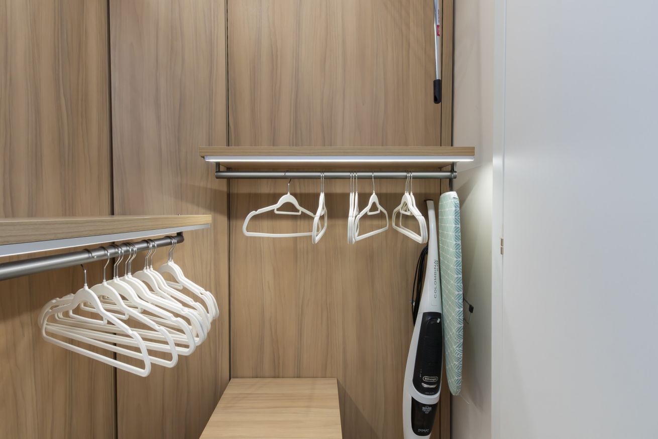 A wooden wardrobe with a hanging rack and a wall-mounted drying rack.