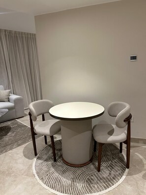 Un coin repas comprenant une table ronde et deux chaises, un canapé et un tapis à motifs.
