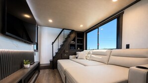 Un interno moderno con un divano, una scala e una TV fissata alla parete.
