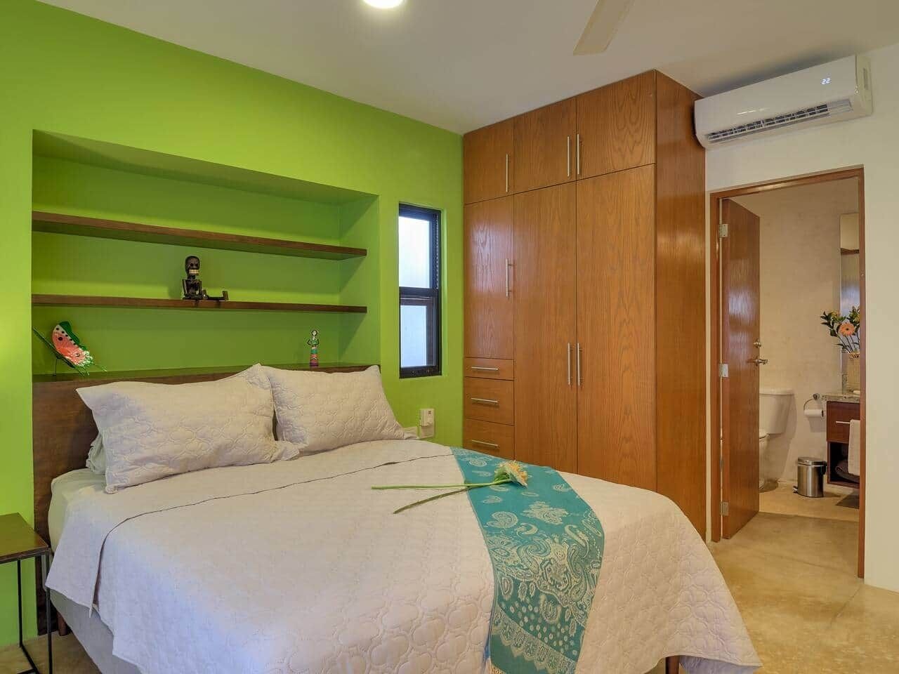 Ein Schlafzimmer mit Bett, Kleiderschrank, Ablagefläche und einem Fenster.