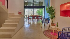 A modern interior with a staircase, a dining area with a table and chairs, a potted plant, and a small table with a wine bottle. - Casa Chopin Stylish Home in Santiago (Mérida)