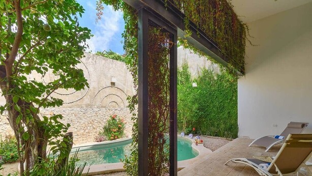 A poolside area with a pergola, lounge chairs, and a swimming pool. - Casa Chopin Stylish Home in Santiago (Mérida)