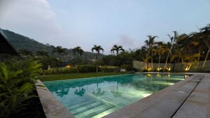 A swimming pool with clear water, surrounded by greenery and palm trees, with a mountain in the background. - Large Farm via Villeta in Closed Condominium (Villeta)