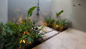 A modern shower area with a wall-mounted fixture, surrounded by lush green plants and a tiled floor. - Large Farm via Villeta in Closed Condominium (Villeta)