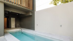 Uma piscina com água azul cristalina, rodeada por um edifício moderno com varanda.