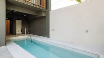 A swimming pool with a clear blue water, surrounded by a modern building with a balcony.