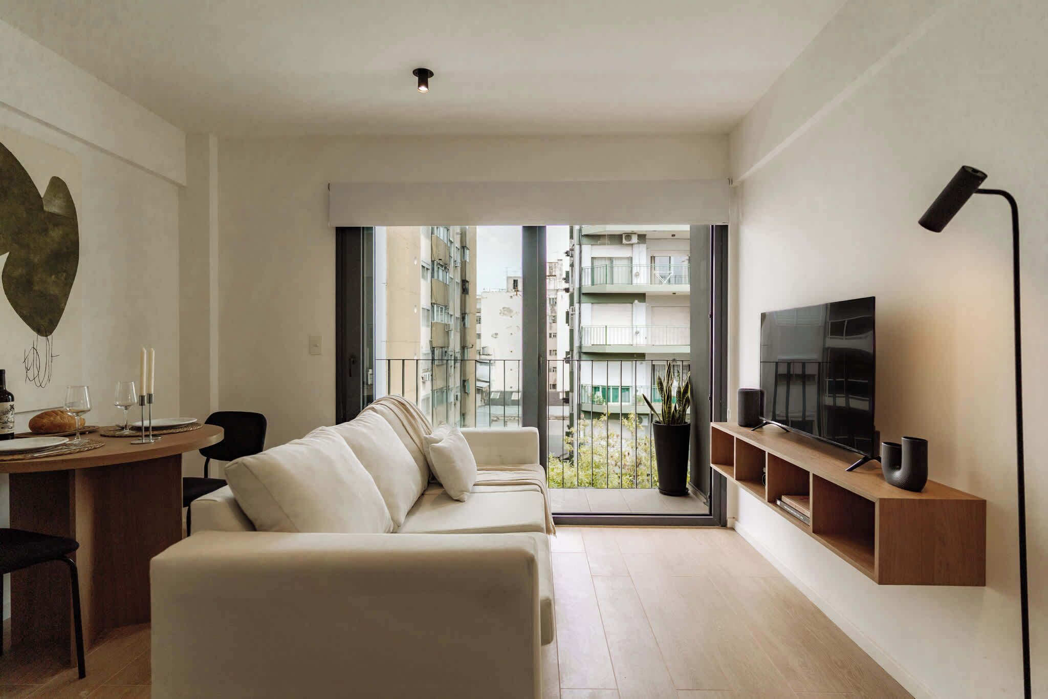 A modern living room with a sofa, TV, and dining area.