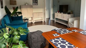 A living room with a blue sofa, a wooden coffee table, and a TV on a stand. - Modern Classic 2 Bed Apartment Near Graves Park (Sheffield)