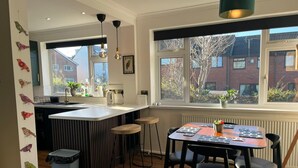 A modern kitchen with a central island, bar stools, and a dining table with chairs. - Modern Classic 2 Bed Apartment Near Graves Park (Sheffield)