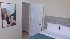 Una stanza con un letto, una porta e un quadro appeso al muro.