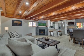 Un vaste espace de vie comprenant un salon avec cheminée, une cuisine et un coin repas.