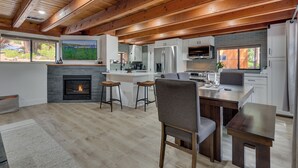 Una cocina moderna con vigas de madera, una chimenea y una isla grande con taburetes.