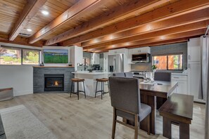 Une cuisine moderne avec des poutres en bois, une cheminée et un grand îlot central doté de tabourets.
