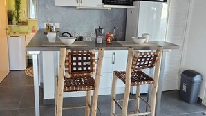 A kitchen with a white countertop, two wooden chairs, a microwave, and a refrigerator. - Incredible sea view apartment 🌊 - Swimming pool - Terrace - (Saint-Martin)