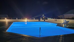 A swimming pool with a deck, lounge chairs, and a distant view of a building. - Incredible sea view apartment 🌊 - Swimming pool - Terrace - (Saint-Martin)