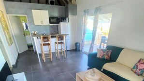 A living room with a sofa, a coffee table, and a kitchen area with a microwave and cabinets. - Incredible sea view apartment 🌊 - Swimming pool - Terrace - (Saint-Martin)
