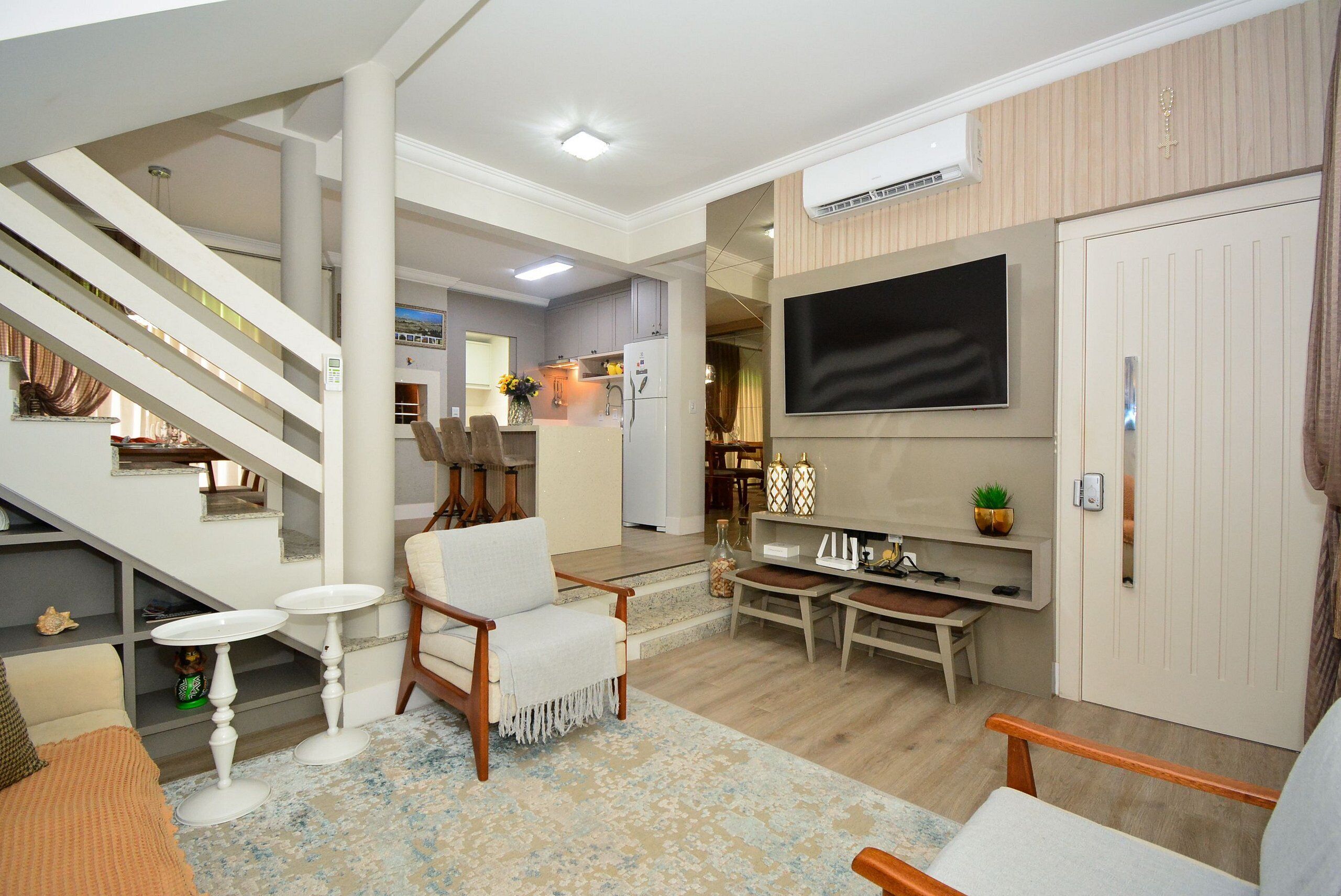 Ein Wohnzimmer mit Treppe, Essbereich und an der Wand befestigtem Fernseher.