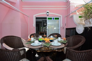 A dining table set with chairs, a window with curtains, and a door with a light fixture.