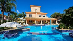 Un hôtel doté d’une piscine, de palmiers et d’une terrasse carrelée.