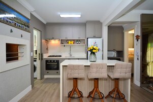 Una cocina moderna con una isla central, taburetes de bar, microondas y refrigerador.