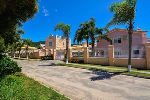 A residential street with houses, palm trees, and a clear blue sky.