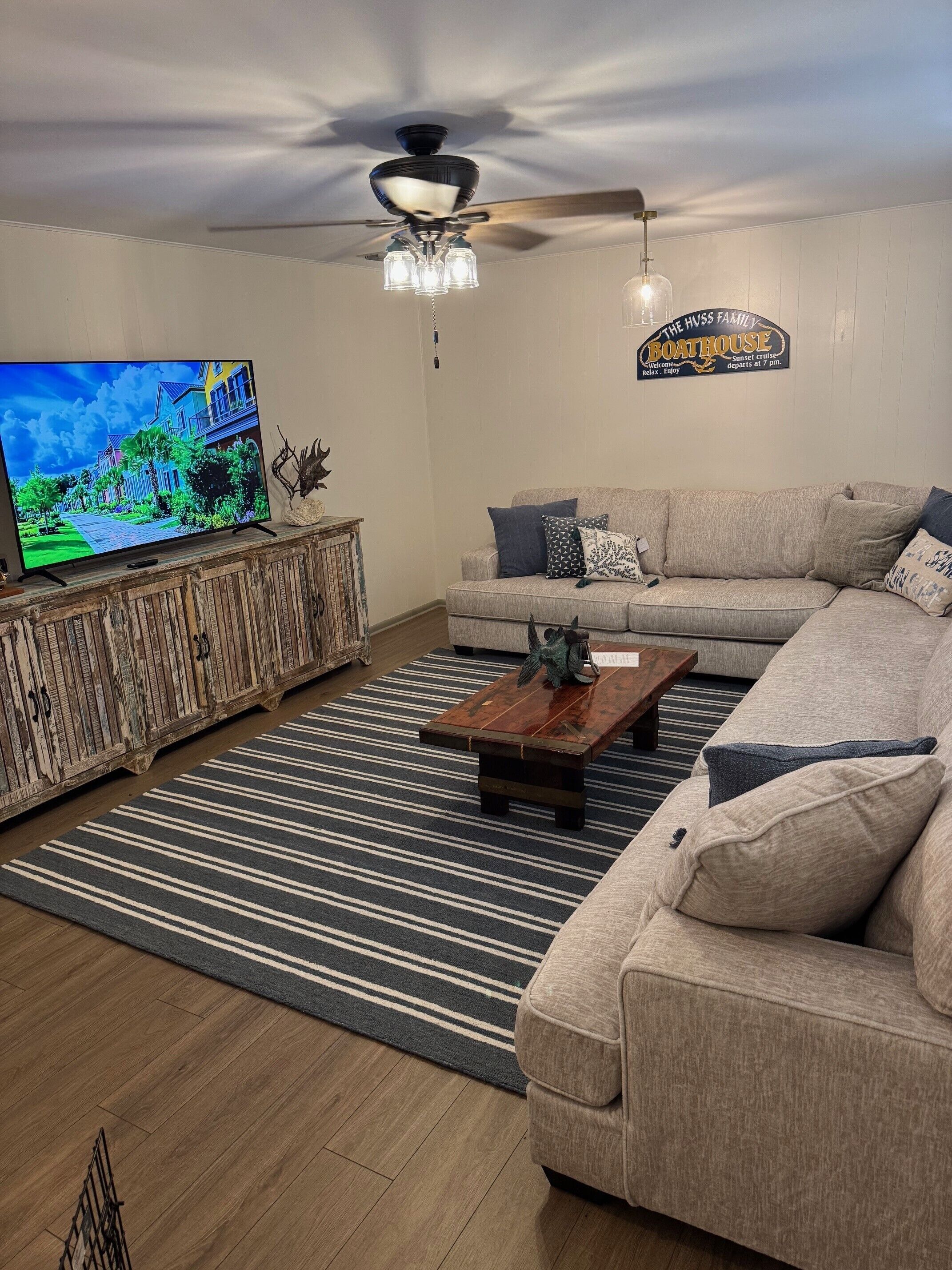 A living room with a television, sofa, coffee table, and a ceiling fan.