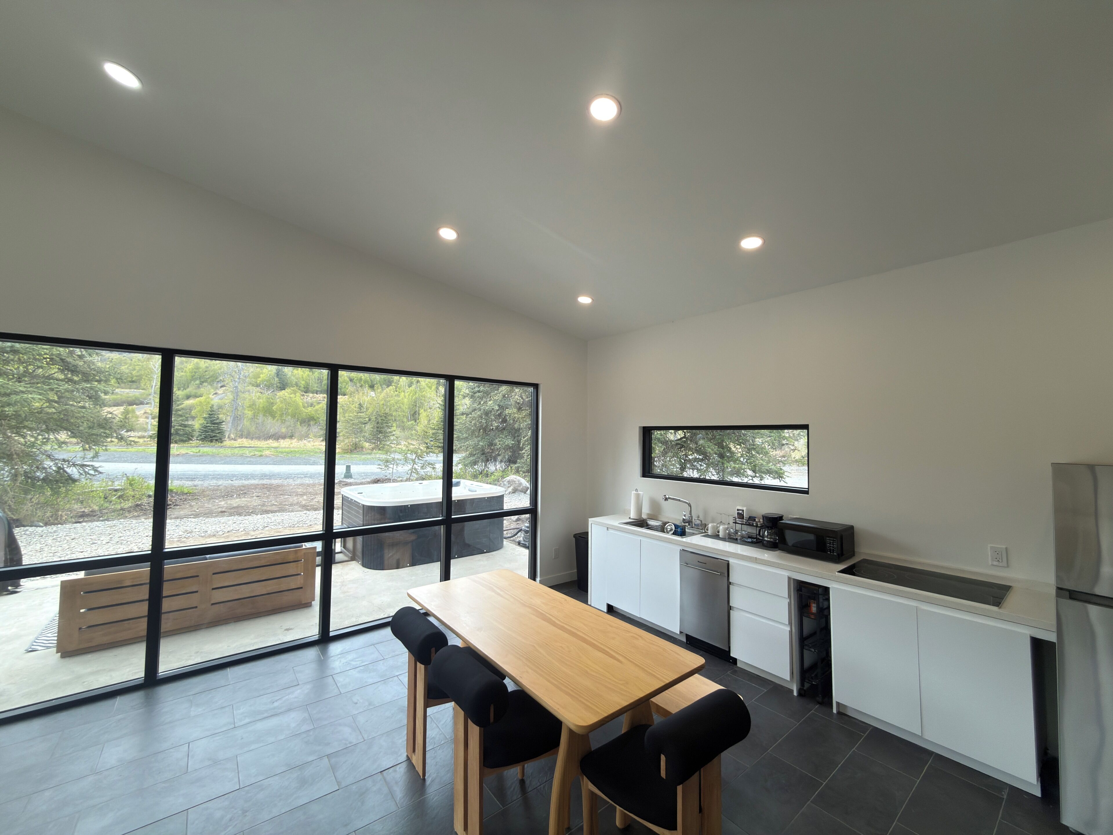 Una cocina moderna con un ventanal grande, una mesa de comedor de madera y un horno empotrado.