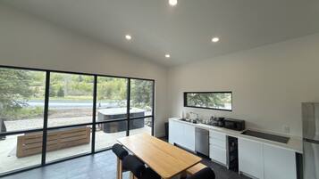 Una cocina moderna con un ventanal grande, una mesa de comedor de madera y un horno empotrado.