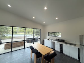 Una cocina moderna con un ventanal grande, una mesa de comedor de madera y un horno empotrado.