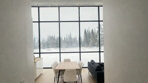 A modern interior with a large window, a dining table with chairs, and a sofa.