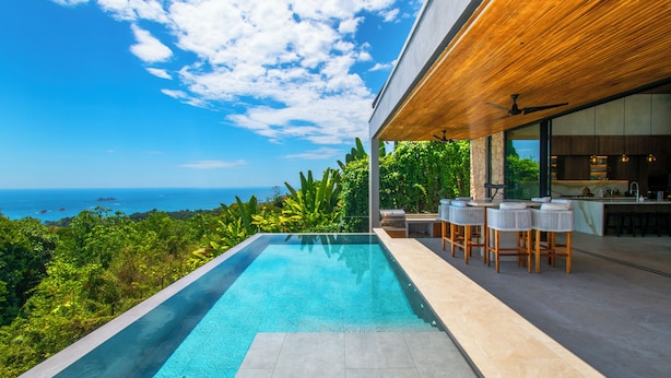 Une piscine extérieure moderne avec vue sur l’océan, un plafond en bois et un espace bar.