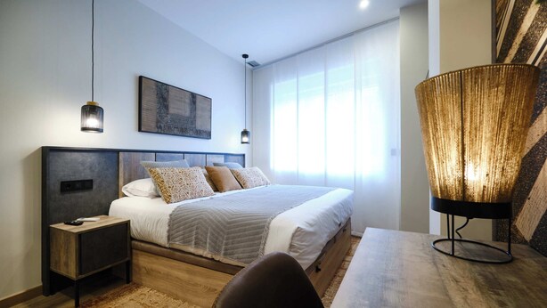 Une chambre à coucher moderne avec un lit, des tables de chevet, un tapis et une grande lampe sur pied.