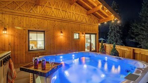Une cabane en bois dotée d’un bain à remous, de murs en bois et de fenêtres.