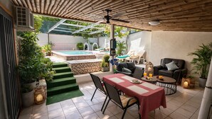 Une terrasse avec une table à manger, des chaises, une piscine et des chaises longues.