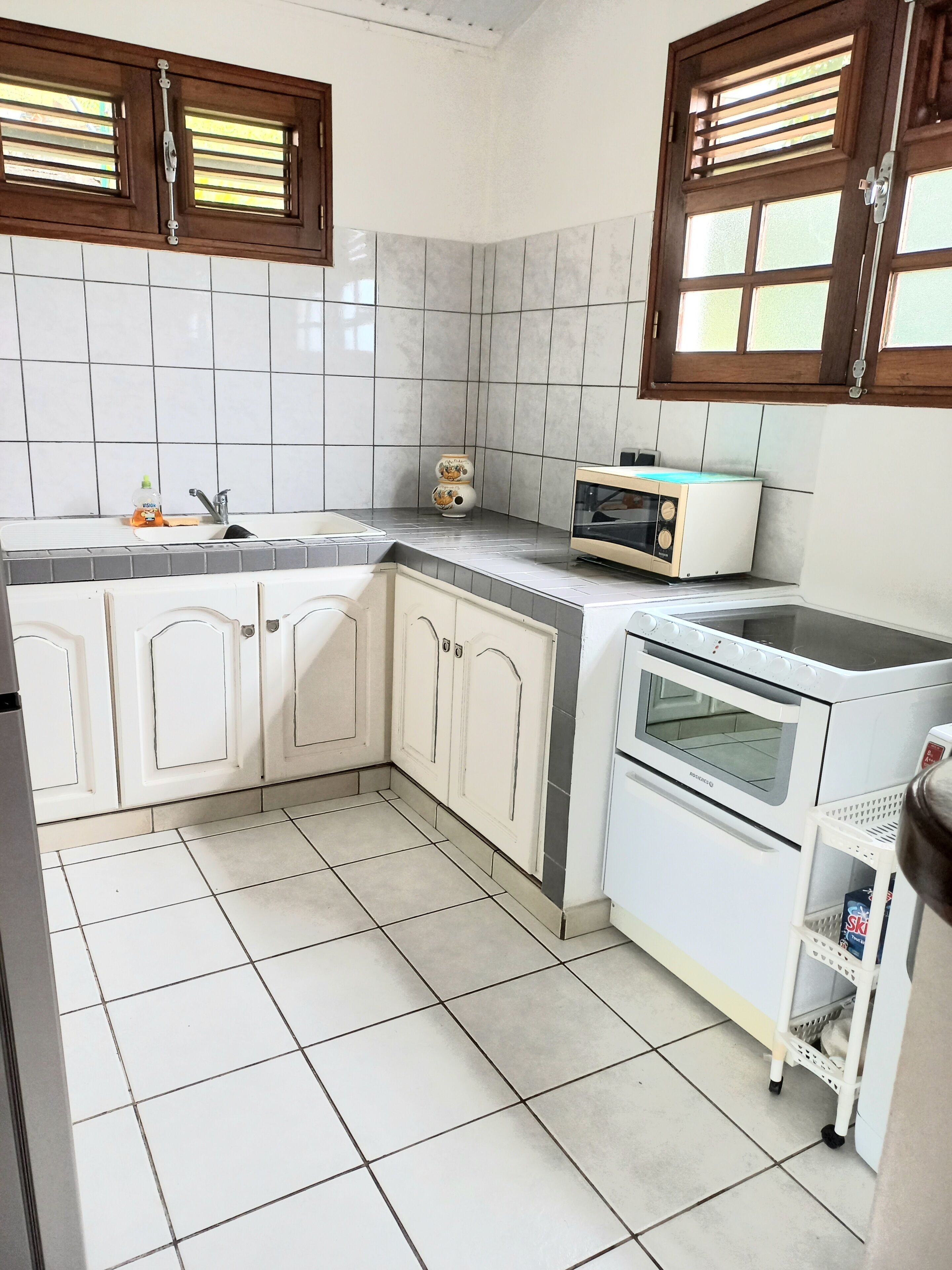 A kitchen with white cabinets, a microwave, a toaster, and a sink.