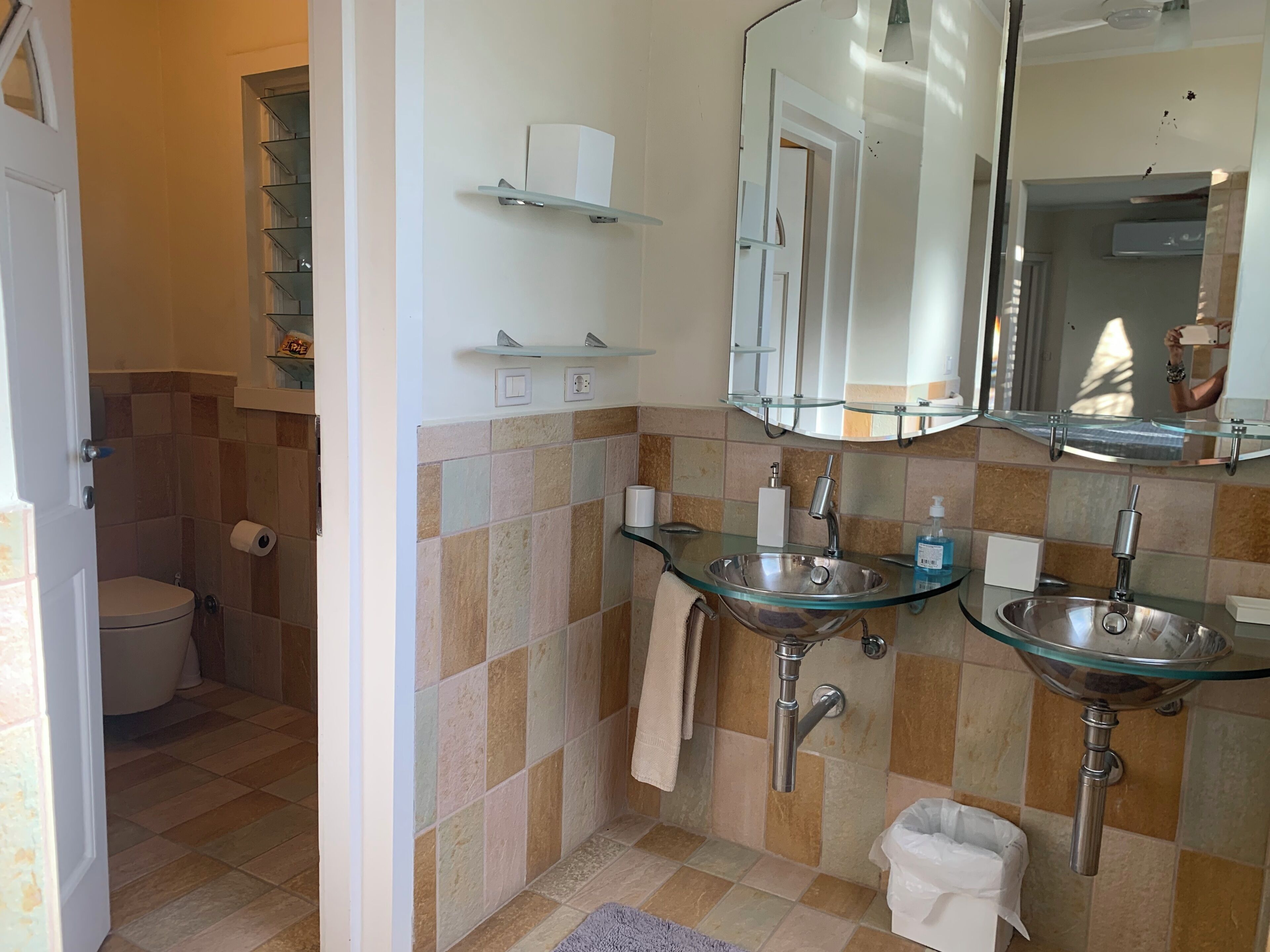 Une salle de bain comprenant des toilettes, deux lavabos, un miroir et un porte-serviettes.