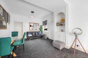 A modern living room with a sofa, chairs, a coffee table, a floor lamp, and a bookshelf. - 360 The Haven. A cosy home in the heart of Greenwich (London)