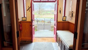 A room with a bed, a fire extinguisher, a door leading outside, and a view of the outside landscape. - Kaber Chapel (Kirkby Stephen)