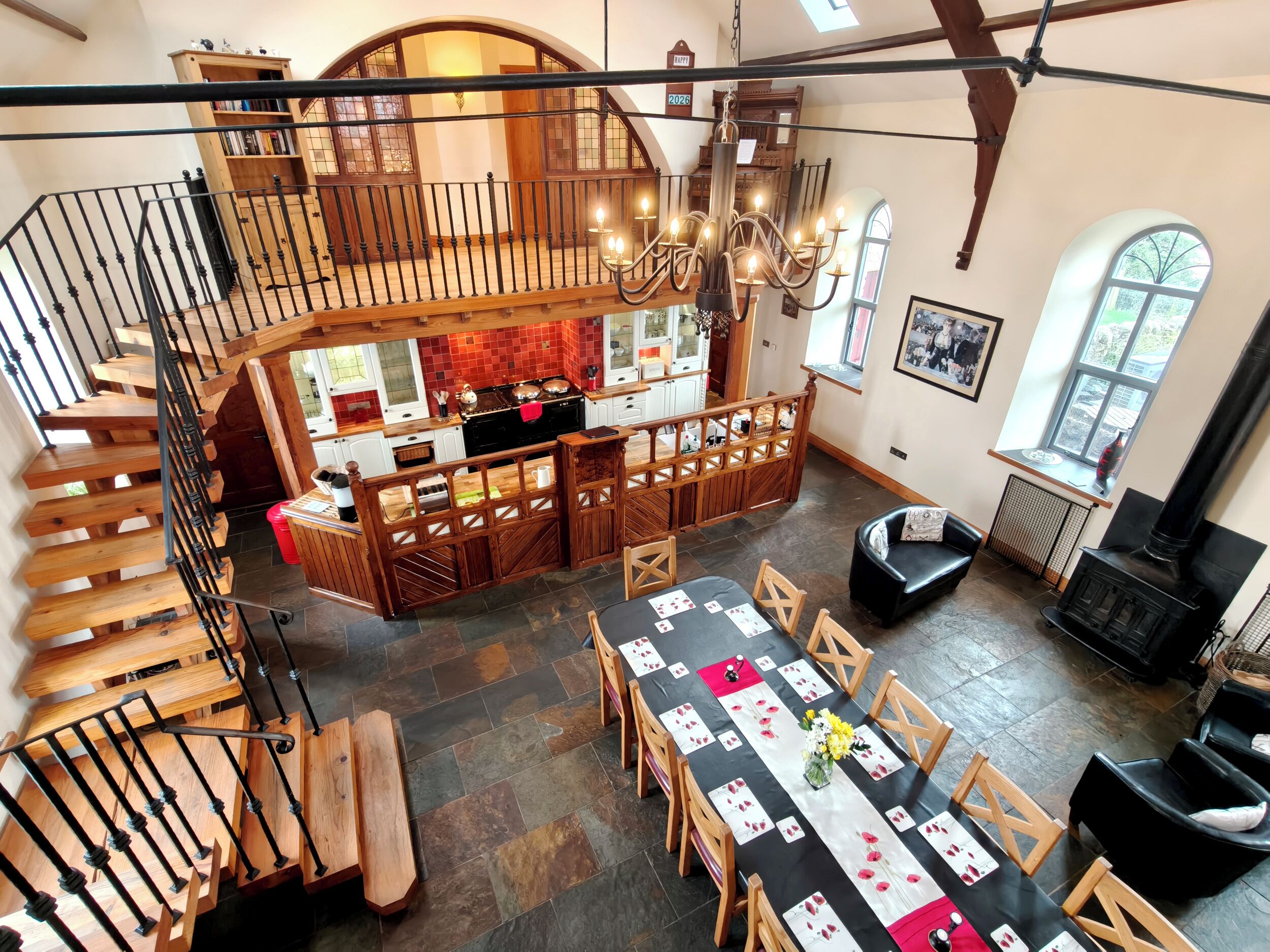 Ein großzügiger Loft-Raum mit hohen Decken, einer Holztreppe, einem Essbereich mit langem Tisch und einer Küche mit einer großen Kochinsel.