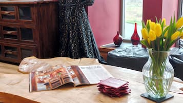 A wooden table with a magazine, a stack of red cards, and a vase with yellow flowers.