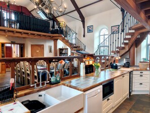 Una cocina amplia con una isla grande, vigas de madera, una escalera y vistas al piso superior.