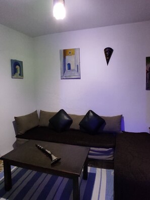 Una habitación con un sofá, una mesita y un cuadro en la pared.