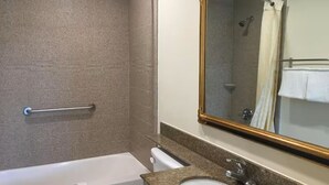 Un baño con bañera, lavabo, espejo y toallero.