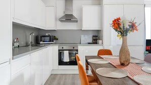 Une cuisine moderne avec des armoires blanches, une hotte de cuisinière en acier inoxydable, un four à micro-ondes et un four traditionnel.