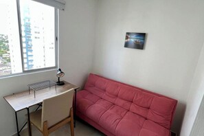 Ein Zimmer mit Schreibtisch, Stuhl und einem roten Sofa.