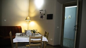 A dining area with a table set for two, a lamp, and a door leading to a hallway. - Antico Portale (Acquasparta)