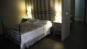A single bed with a metal frame, two bedside tables with lamps, a striped wall, and a door leading to another room. - Antico Portale (Acquasparta)