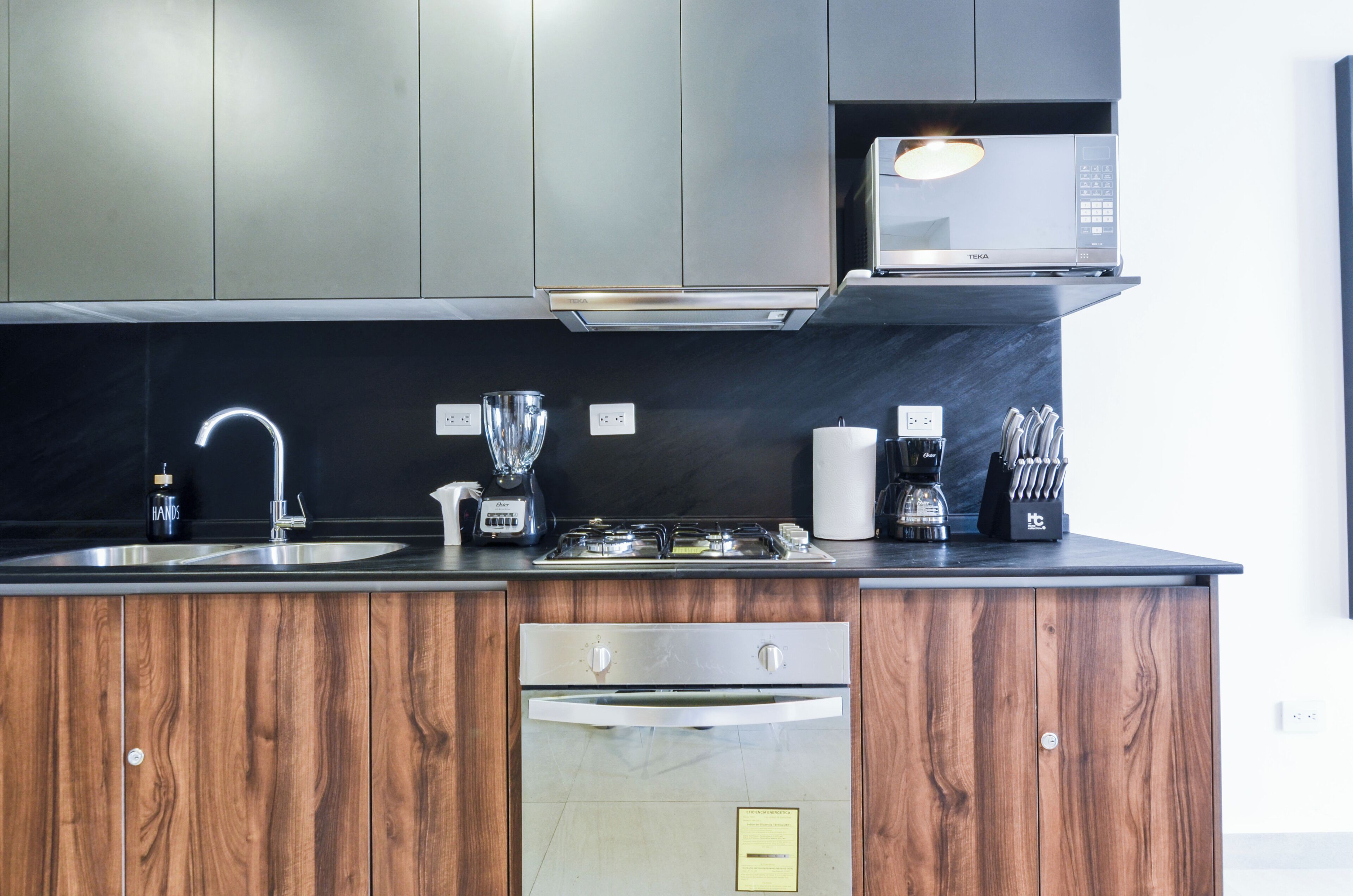 A modern kitchen with stainless steel appliances, wooden cabinets, and a black countertop.