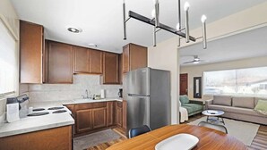 Eine moderne Küche mit Holzschr änken, einem Edelstahlkühlschrank, einem Esstisch mit weißer Tischdecke und einem Deckenventilator im Wohnbereich.